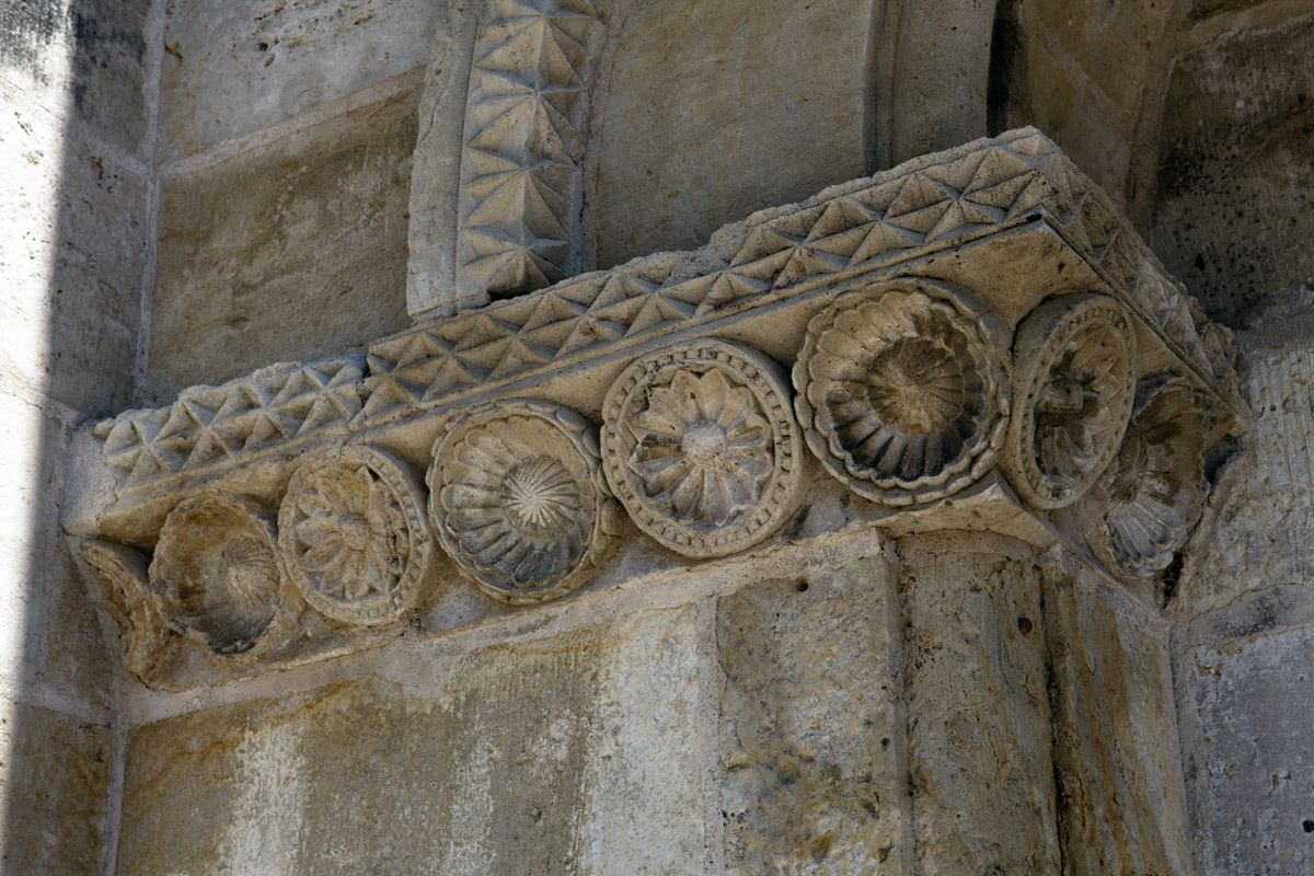 L'imposte de l'arcade aveugle gauche de la façade est ornée de fleurs entourées de cercles.