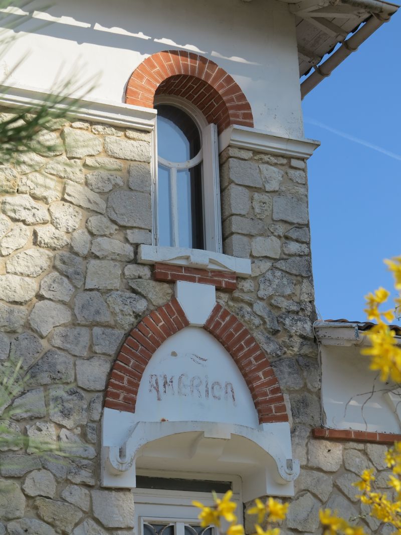 Détail de la façade : parement, décor en brique, cartouche et formes courbes.