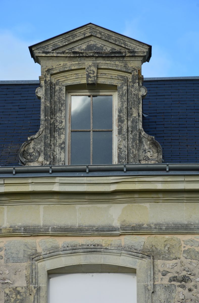 Lucarne flanquée d’ailerons à volutes de l'ancienne école de filles de Chenevelles.