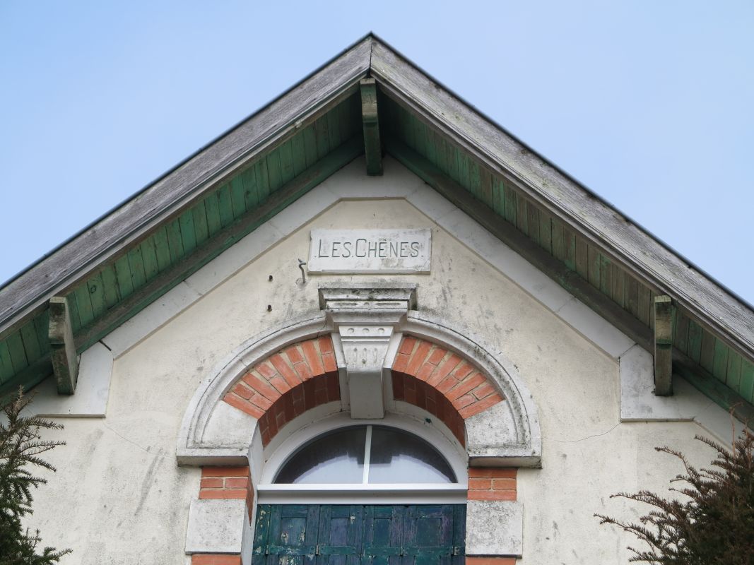 Détail de la façade : pignon, linteau en plein cintre et cartouche.