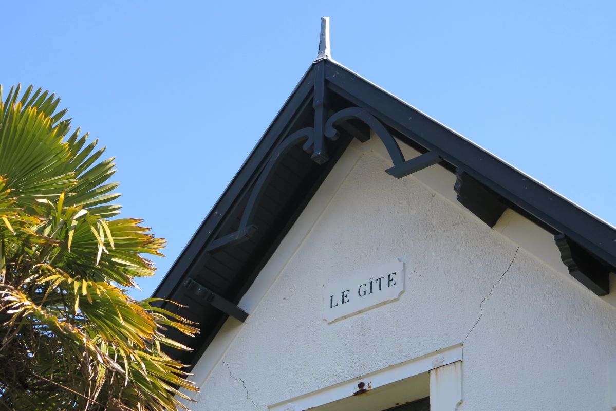 Détail de la partie de façade en pignon : cartouche et ferme de charpente apparente.