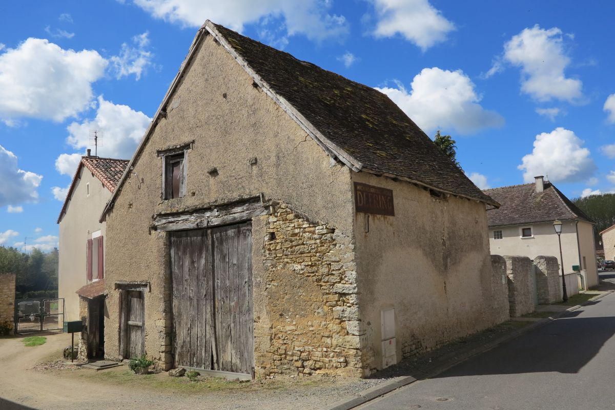 Un lit de pierres épouse la forme des deux poutres qui forme le linteau de la porte charretière de cette grange du bourg.