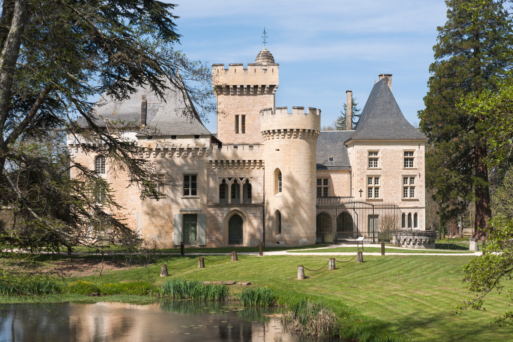 Façades néogothiques du château se reflétant dans le miroir d'eau.