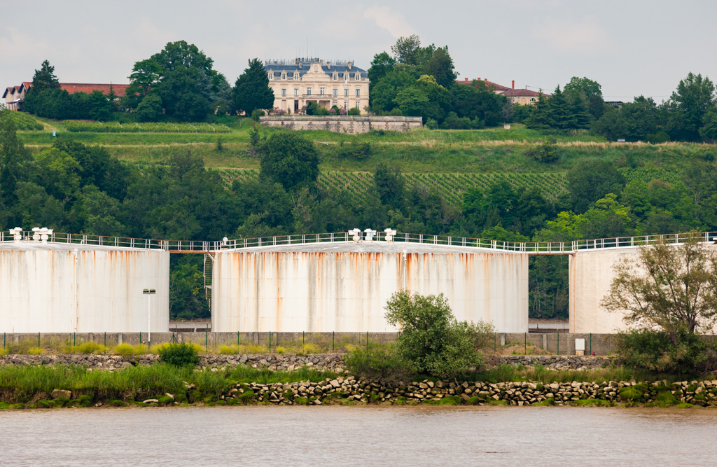 Vue depuis la Garonne, avec au premier plan les cuves du dépôt pétrolier du Bec d'Ambès.