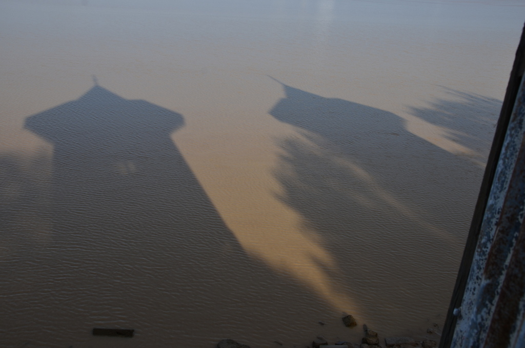 Ombres des kiosques sur les eaux limoneuses de la Garonne.