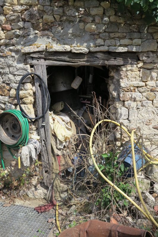 La porte piétonne à encadrement en bois et larmier en pierre qui protège le linteau de la même grange.