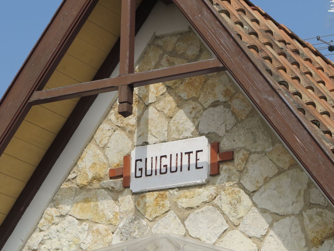 Détail de la façade : ferme de charpente apparente, parement et cartouche.