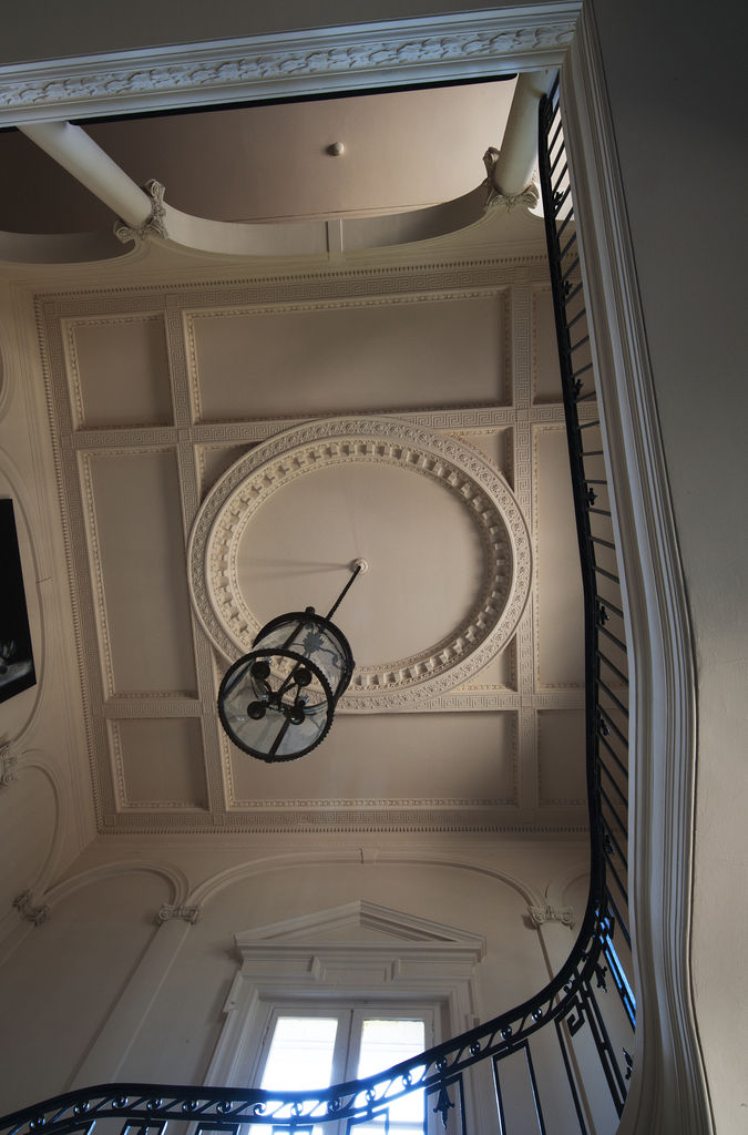 Plafond à décor sculpté de la cage d'escalier vu depuis le rez-de-chaussée.