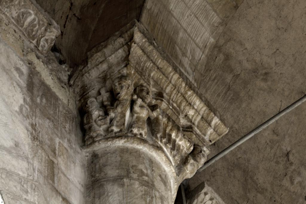 Scène d'enterrement, peut-être d'un prêtre, dans l'église Saint-Pierre à Airvault. Collatéral nord, côté sud, pilier entre la quatrième et la cinquième travées, colonne engagée nord, chapiteau, vue depuis la gauche : personnage porté sur un brancard (funérailles d'un prêtre ?).