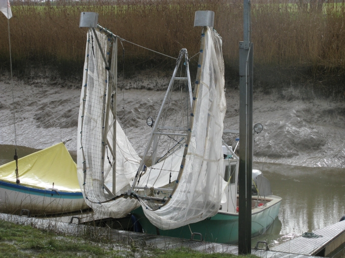 Un bâteau de pêche amarré au port, avec filets relevés.